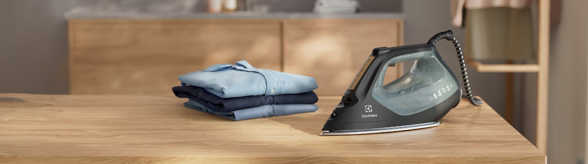 Et strykejern som står på et bord ved siden av en bunke med klær.